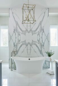 Bathtub against a marble wall and gold light fixture hanging above