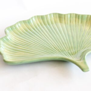 A light green ceramic serving dish shaped like a ginkgo leaf, featuring detailed vein patterns and a glossy finish.
