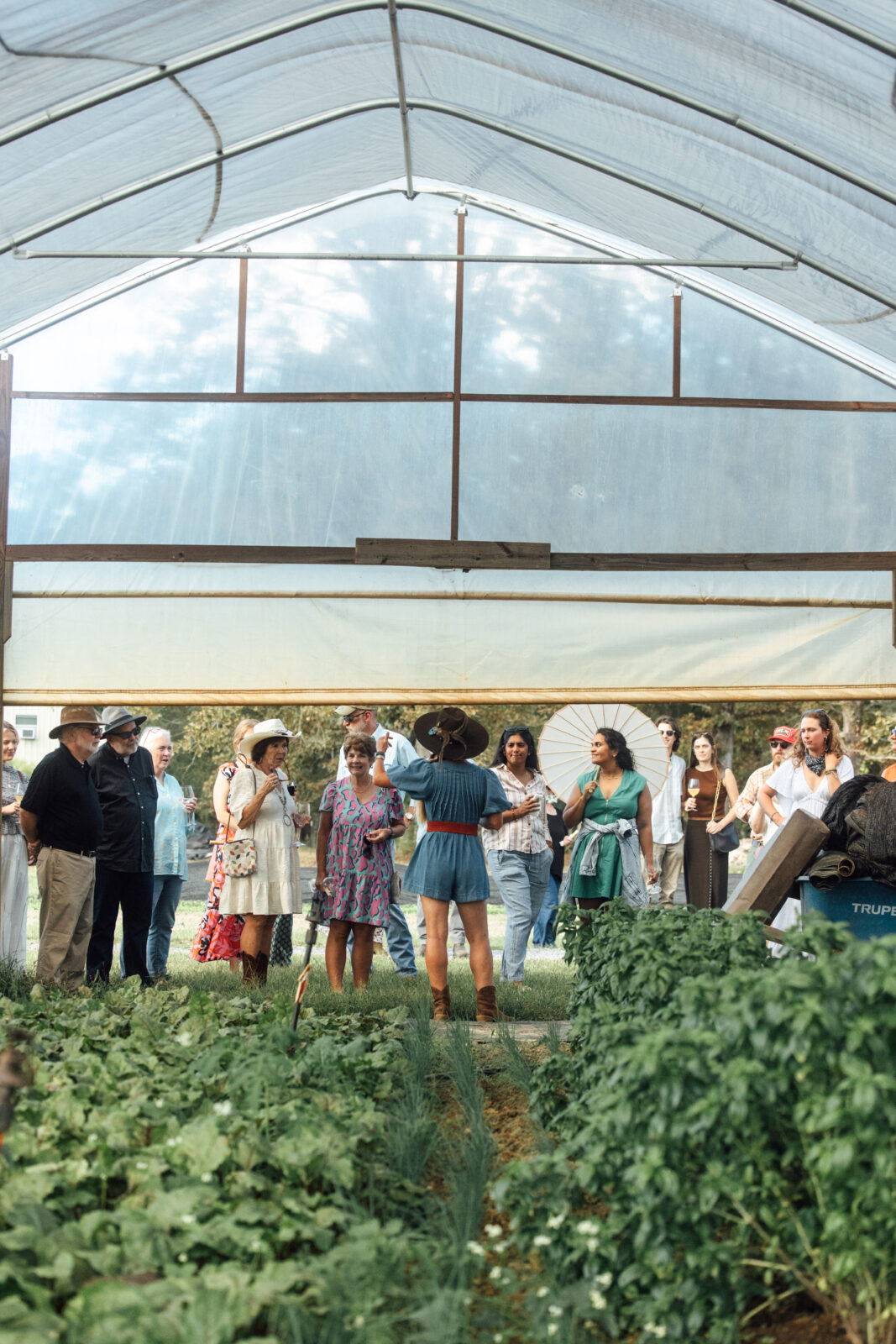 Farmer and group in front of greenhouse