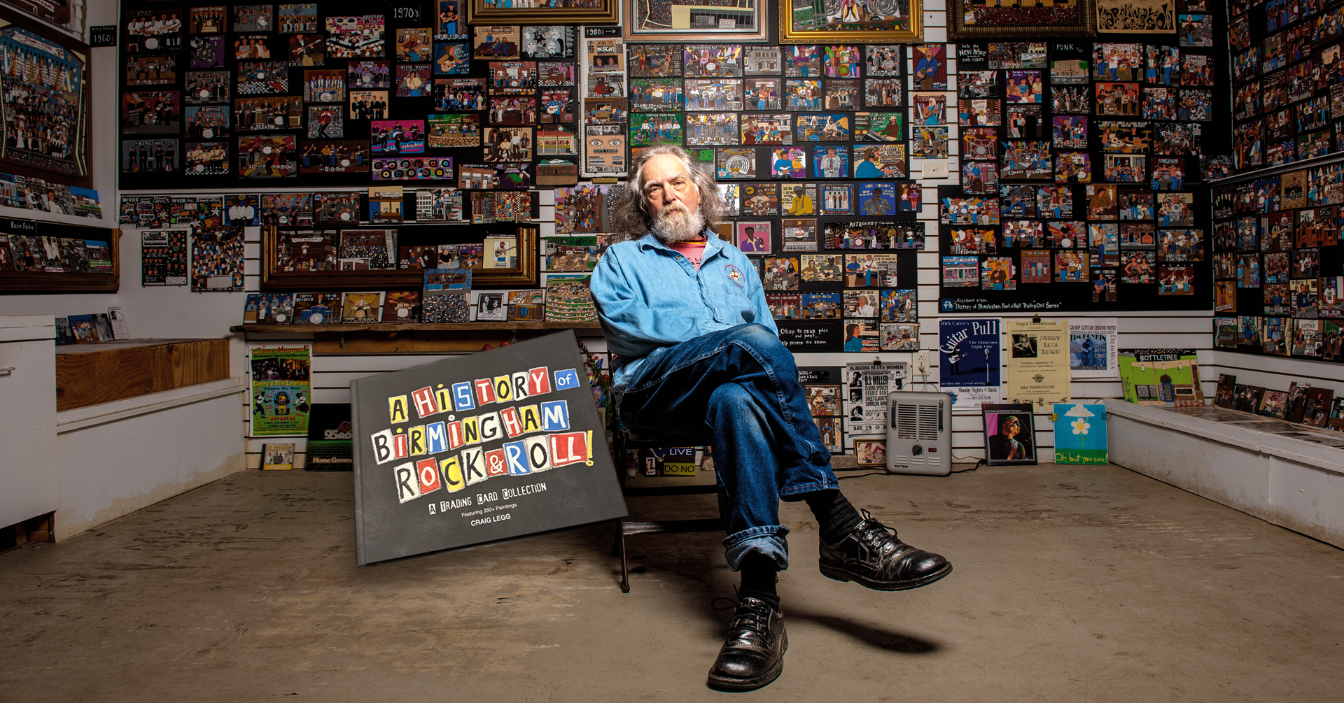 Craig Legg sitting in front of his artwork
